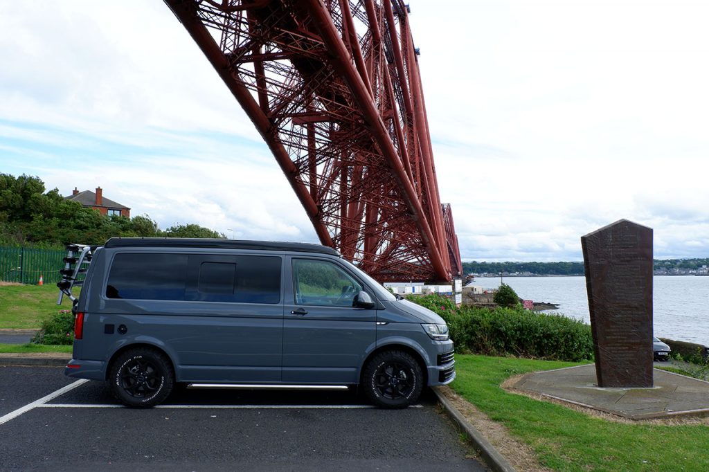 Side of campervan with backdrop of Forth Rail Bridge